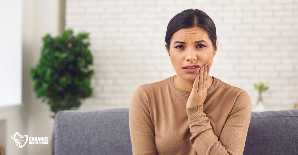 Person resting on a couch with an ice pack on their cheek, recovering from wisdom teeth removal