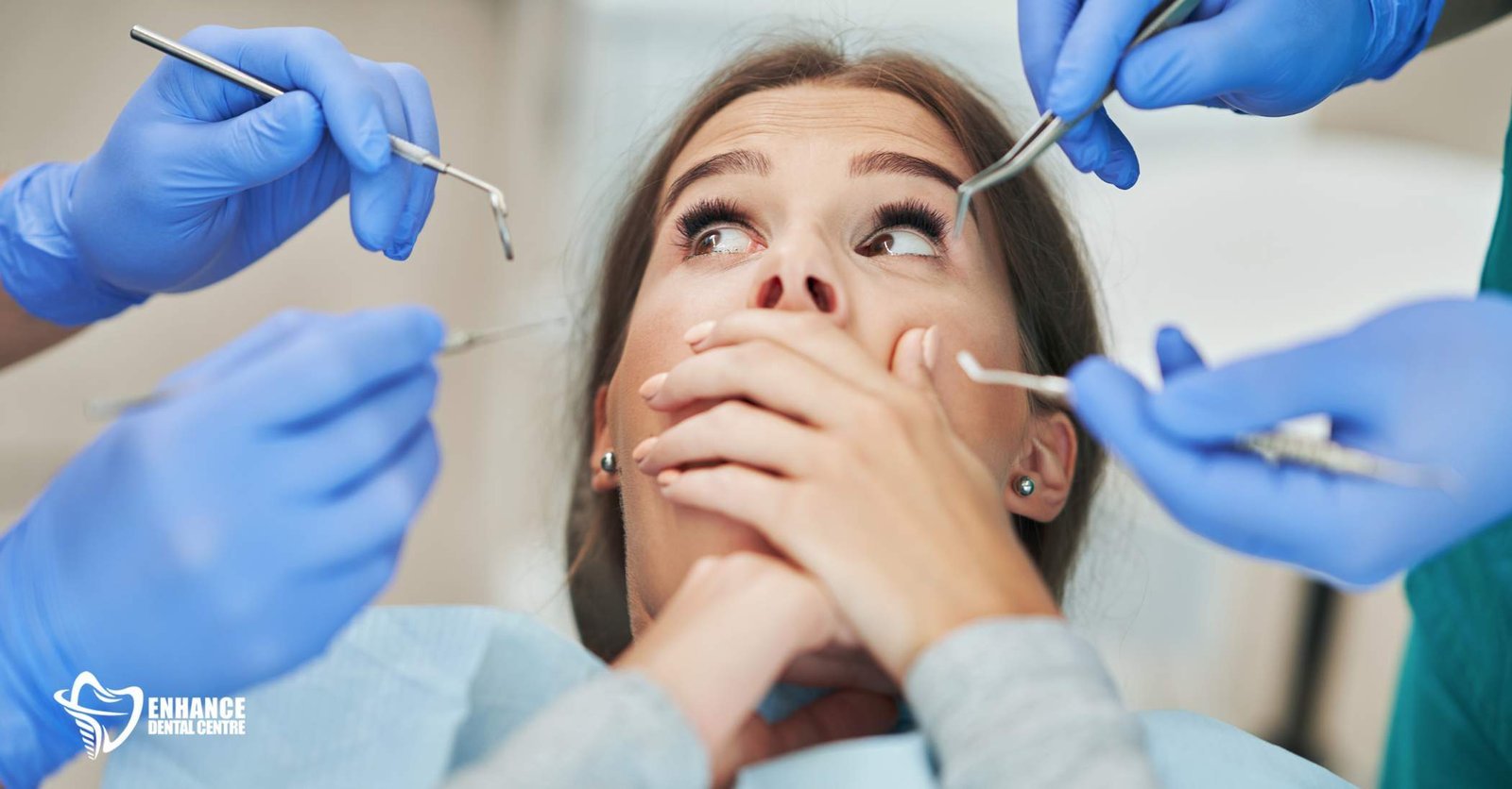 A person in a dental chair, looking anxiously down at their hands, appearing embarrassed.