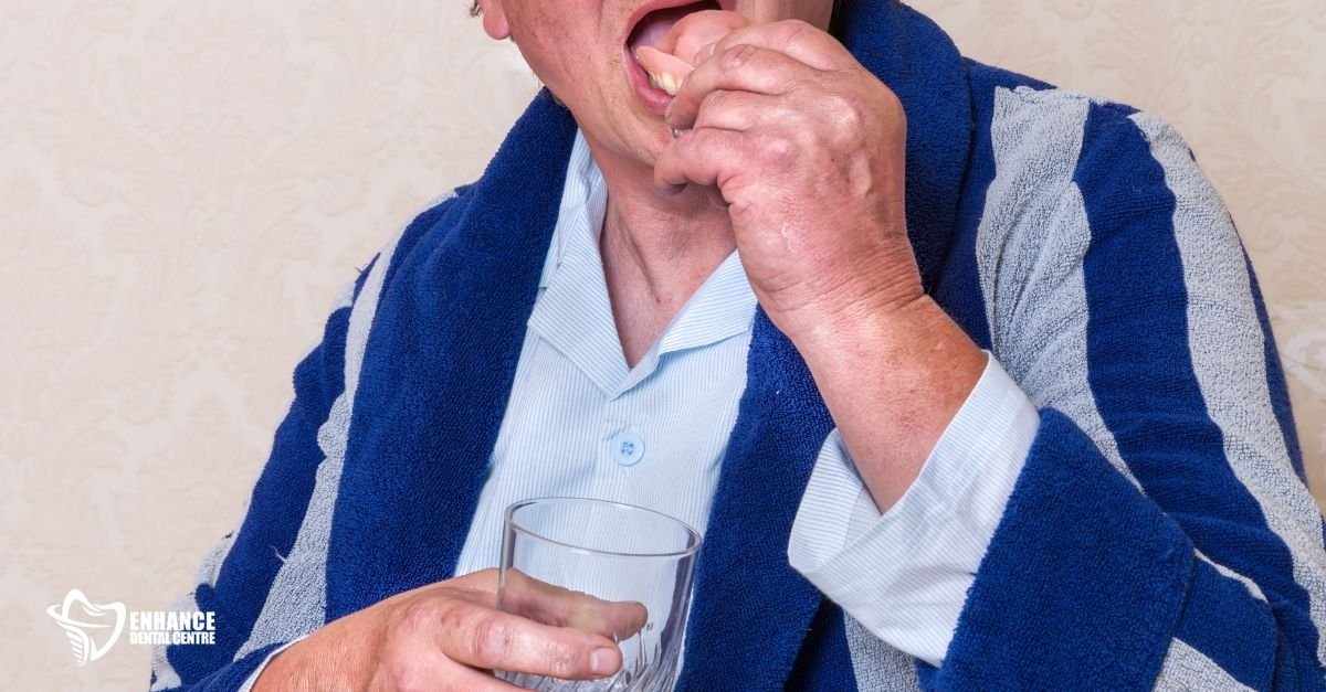 A senior woman holding a glass of water with dentures soaking inside.