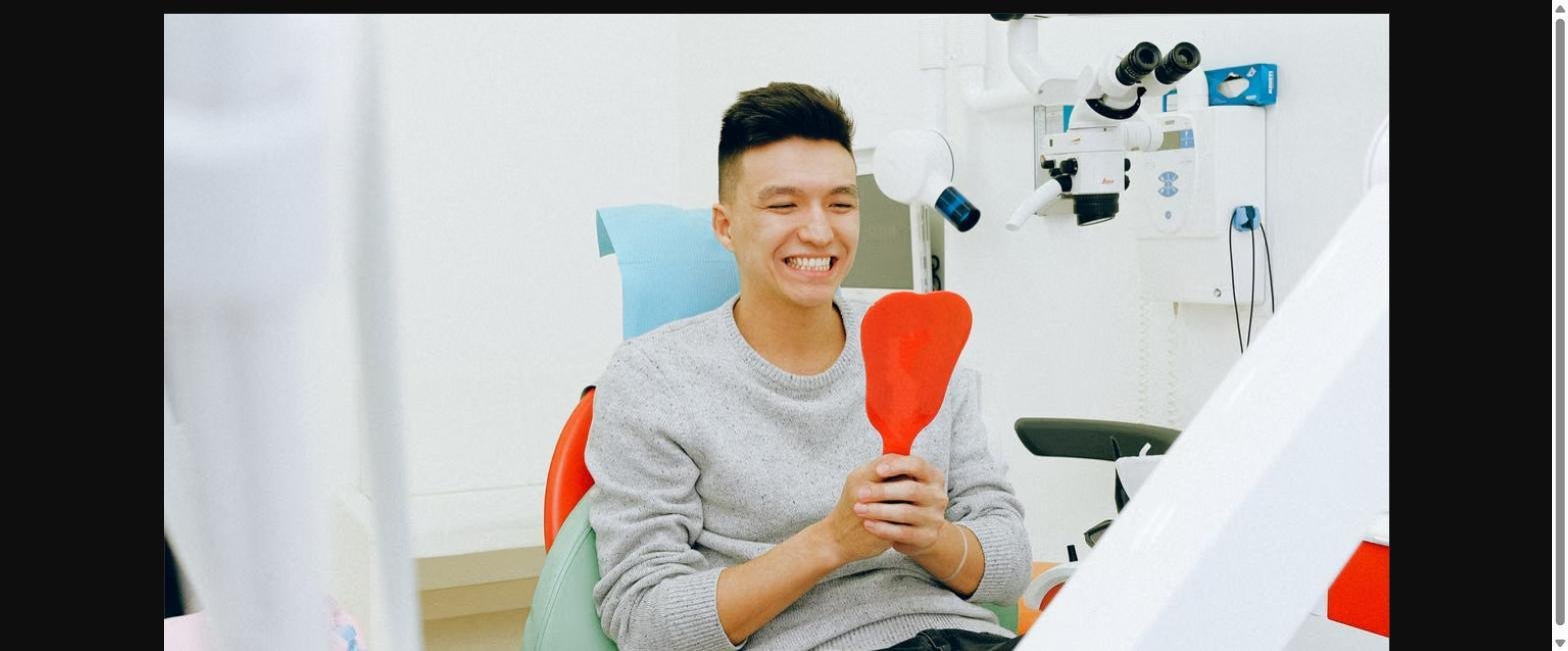 Smiling dental patient holding a mirror after composite bonding at a Kitsilano dental clinic