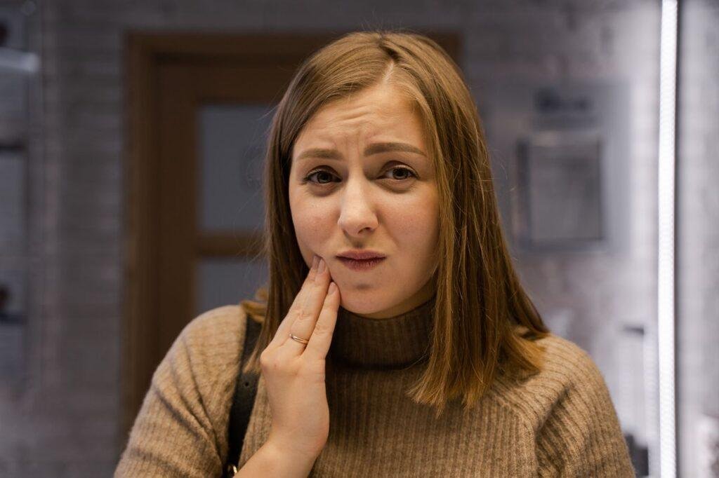 Woman holding her cheek after a dental injury in Vancouver