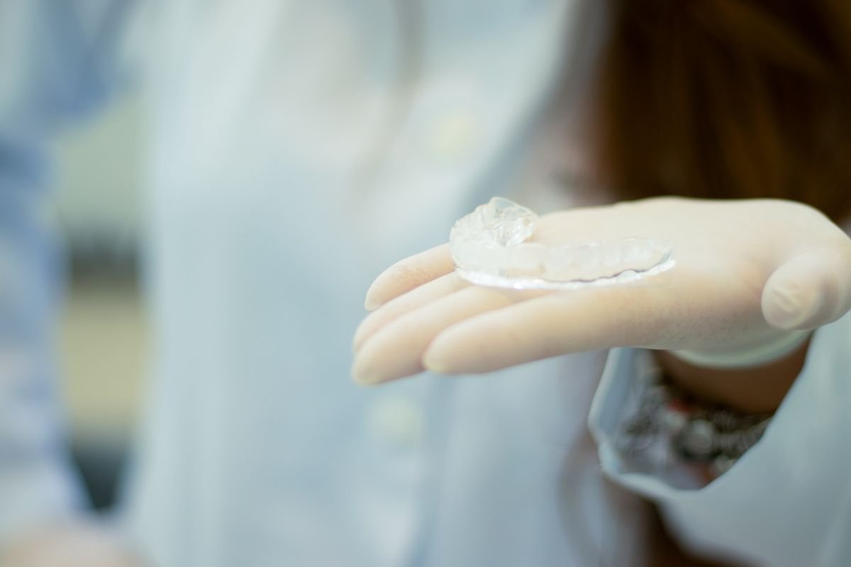 Gloved hands of a dentist holding a retainer