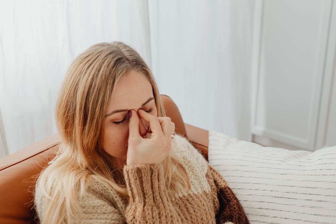 Woman pressing her nose from sinus pressure that is causing upper tooth pain