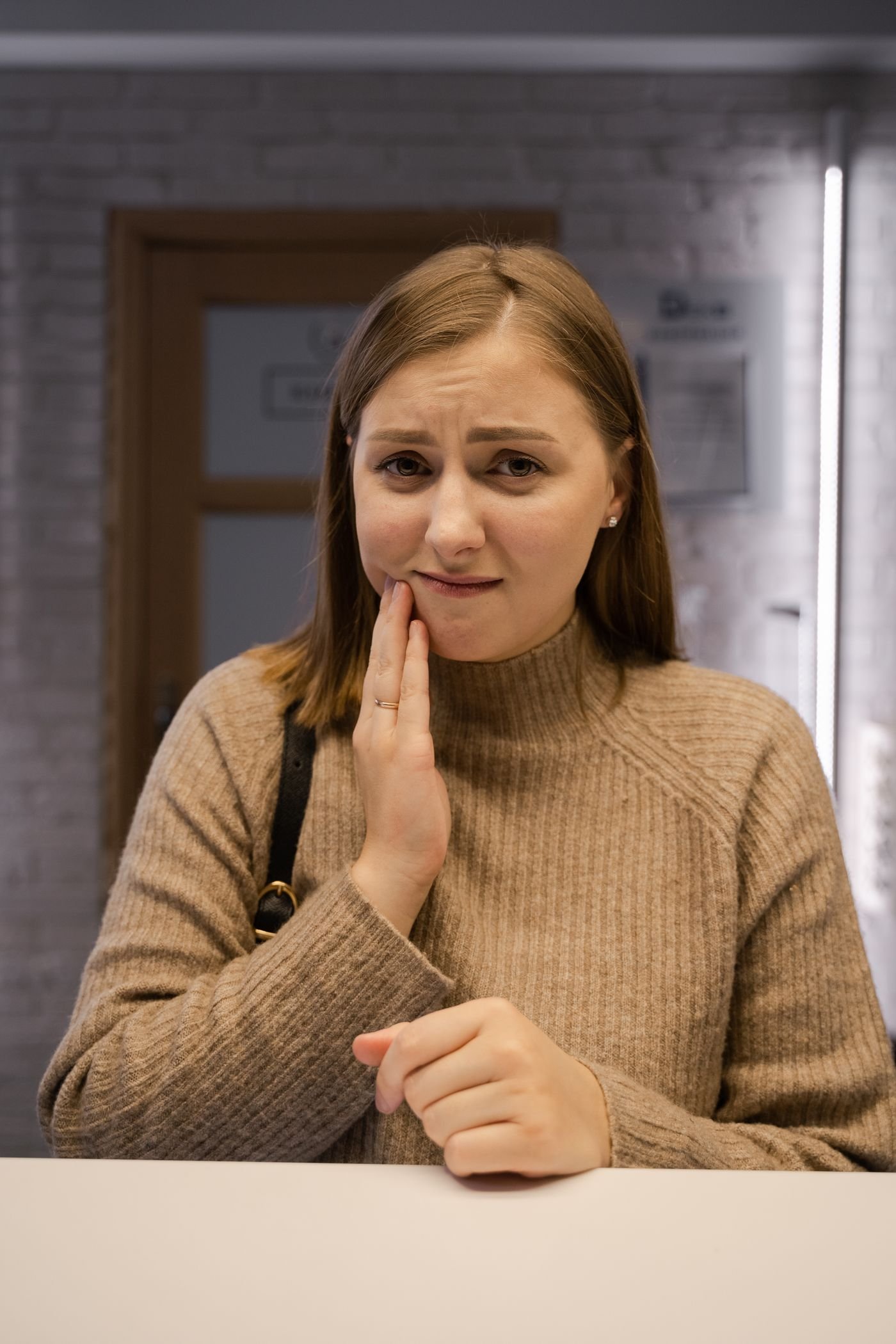 Woman holding her jaw from tooth infection pain before seeing a Vancouver dentist